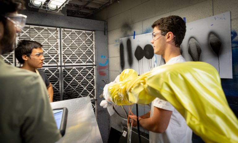 Engineering students working in the automated paint booth